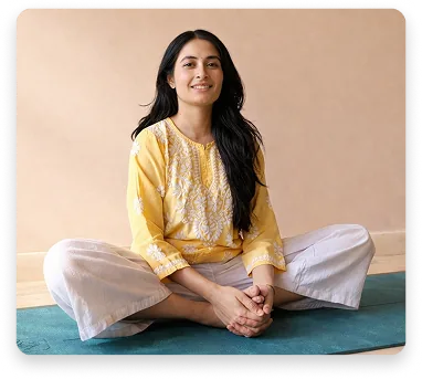A woman seated cross-legged and smiling during a women's wellness class